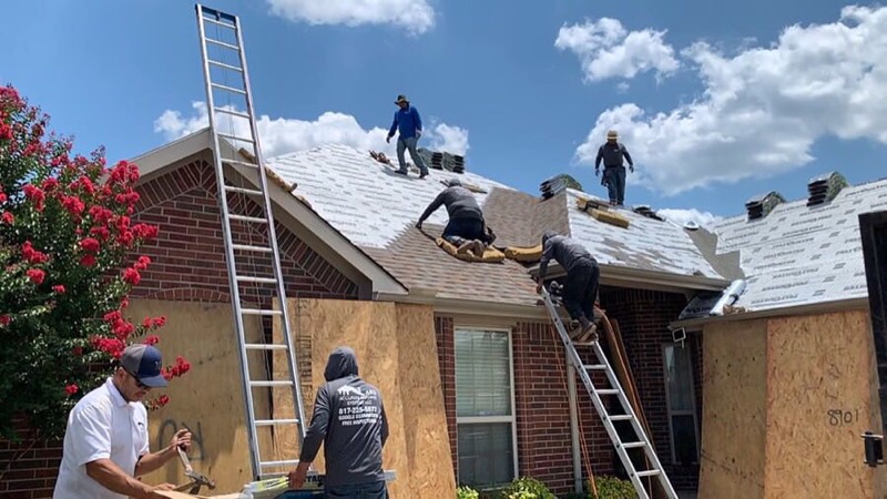 Roofing crew installing shingles on a residential home in Keller