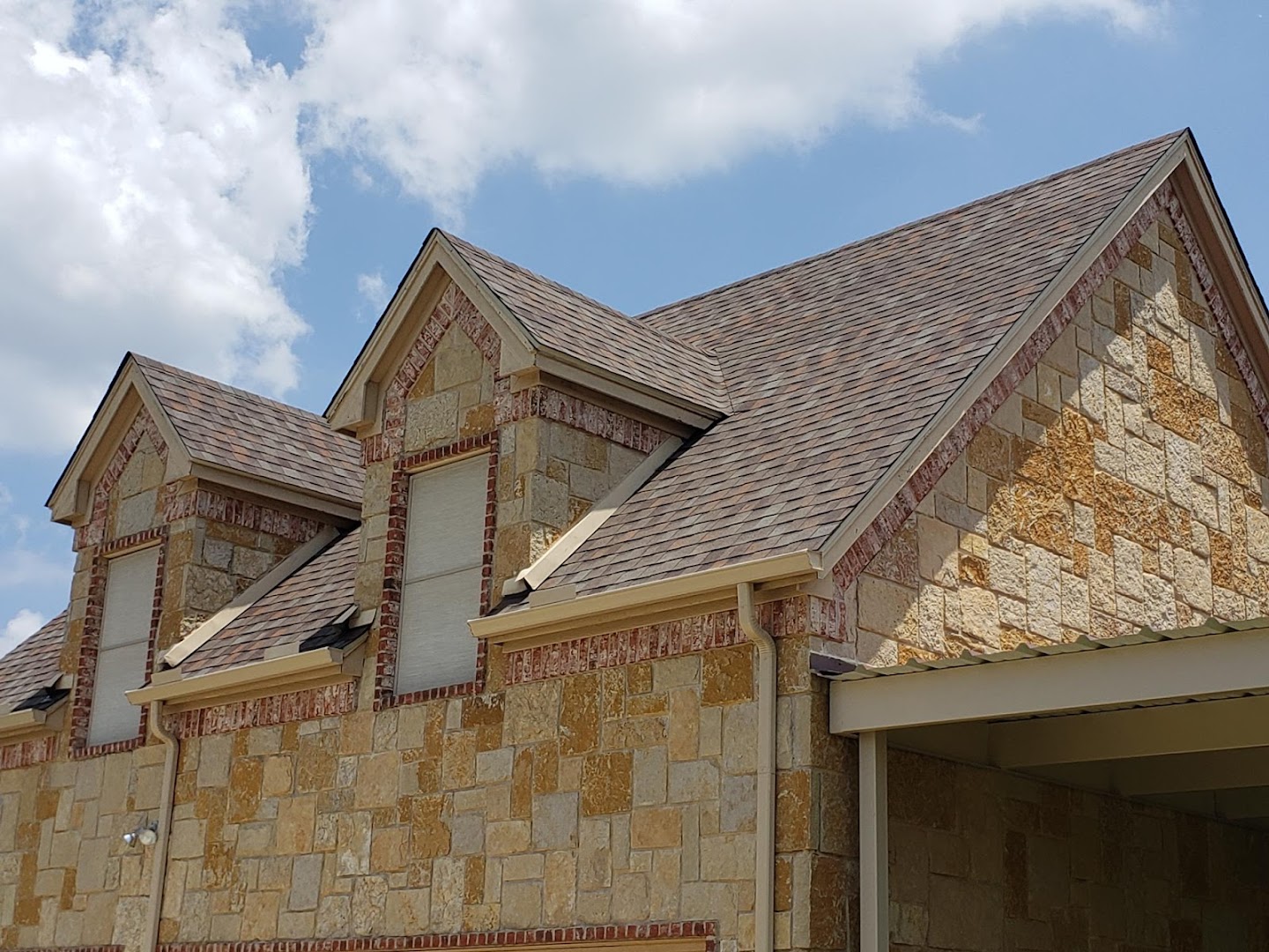 Completed shingle roof on a stone home in Keller